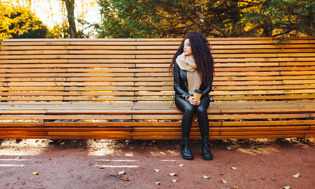 Sad woman sitting on bench in park