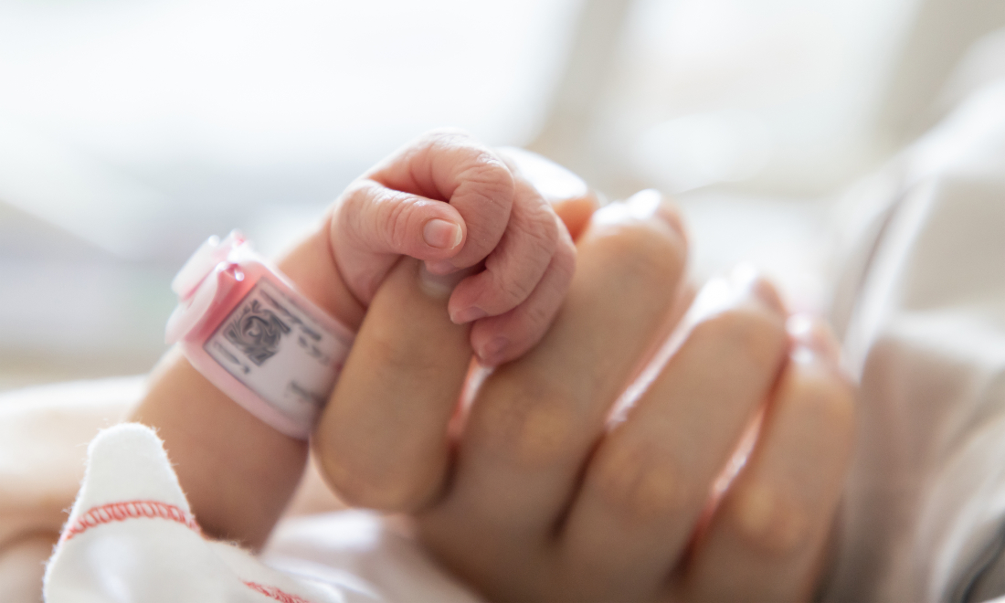 Mother holding the hand of a newborn baby girl