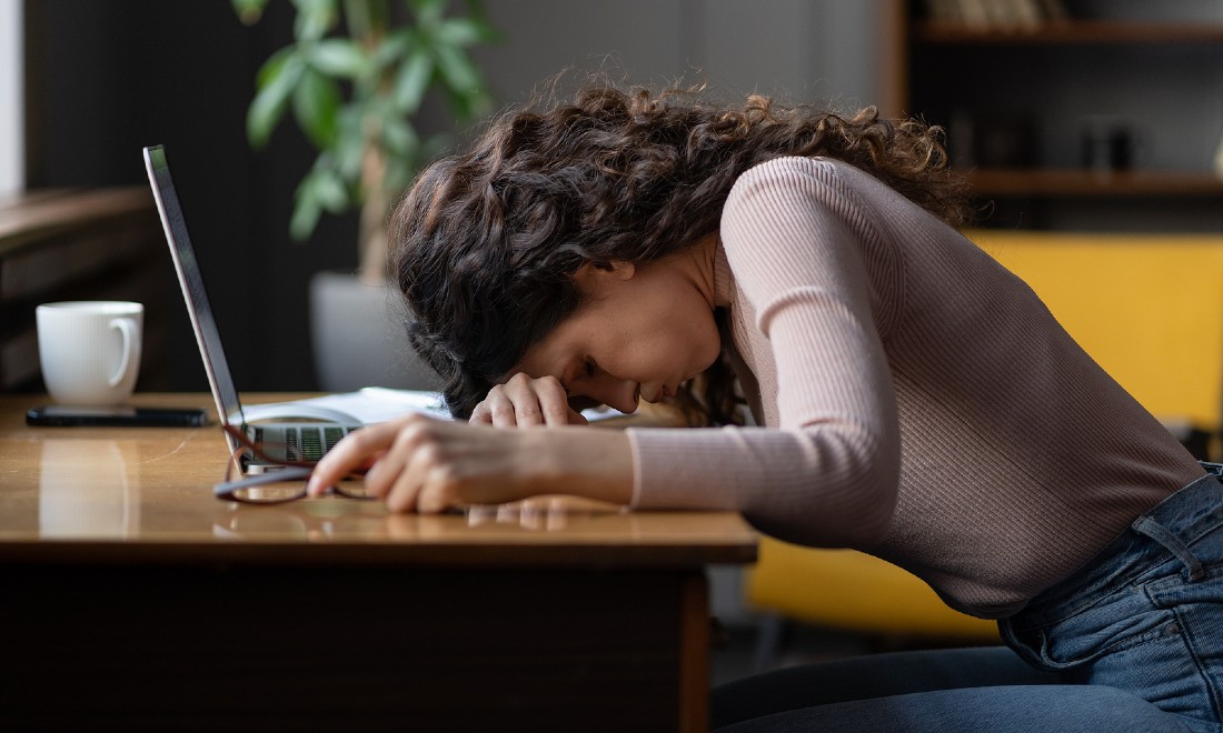 woman head on desk, burnout symptoms