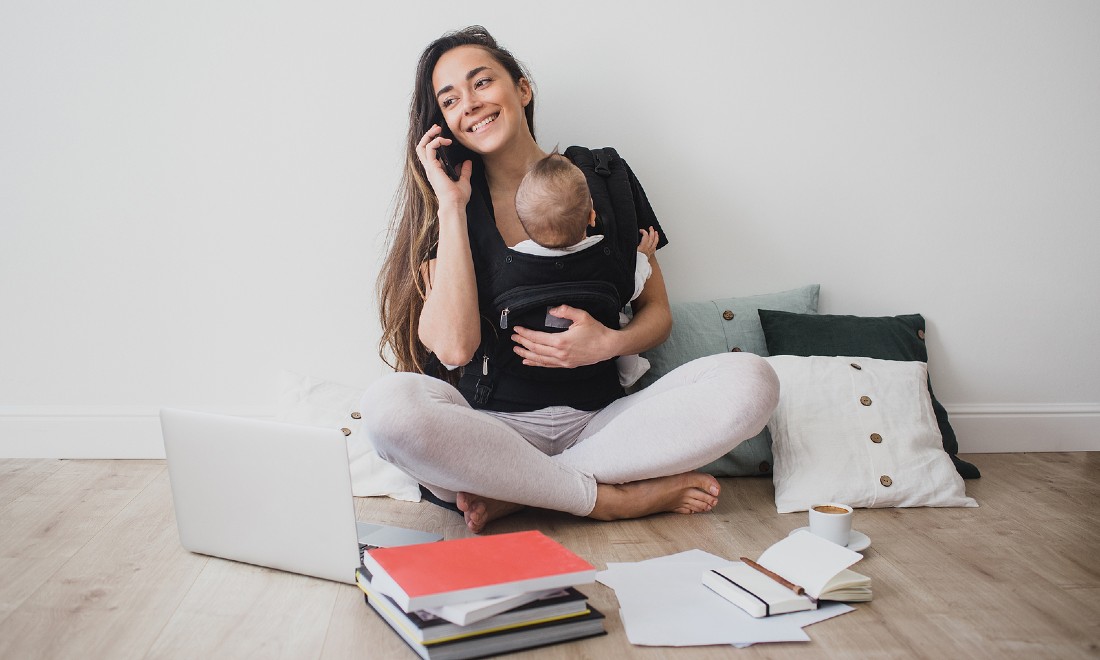 woman holding baby while working, sitting on floor