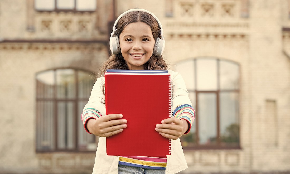 Girl holding audiobook and headphones