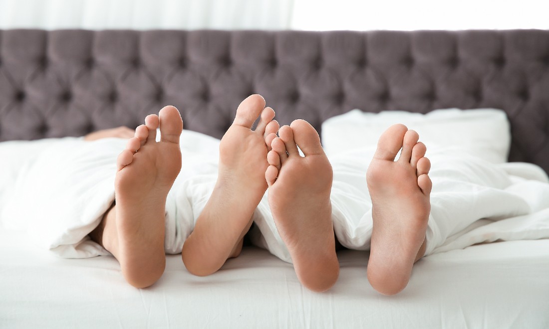 sex during coronavirus pandemic - couple in bed feet sticking out of blanket