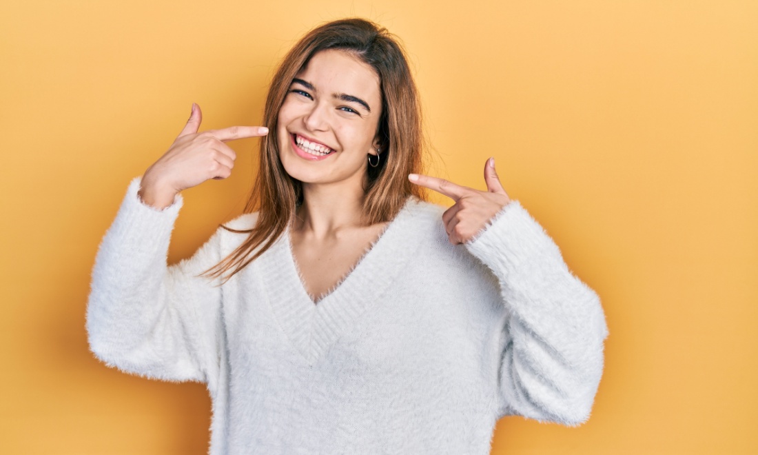 woman pointing at her smile - The future of cosmetic dentistry: Trends in smile makeovers - Parla House of Dentistry