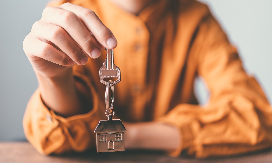 person holding up key with house keychain