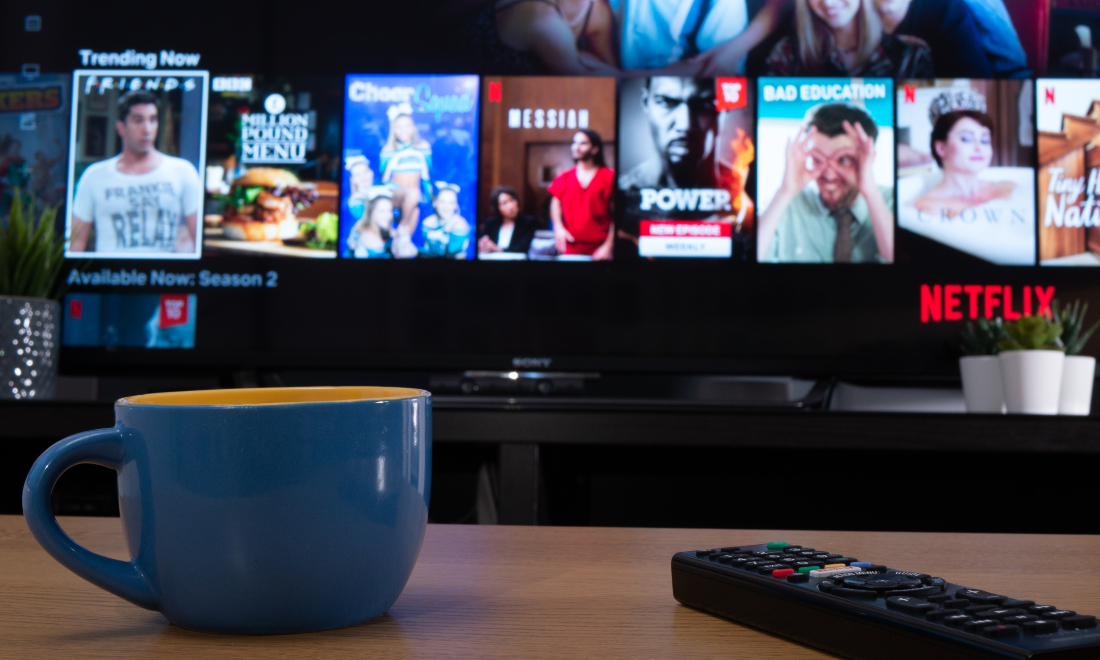 Mug and remote on a coffee table as someone selects something from Netflix to watch on TV