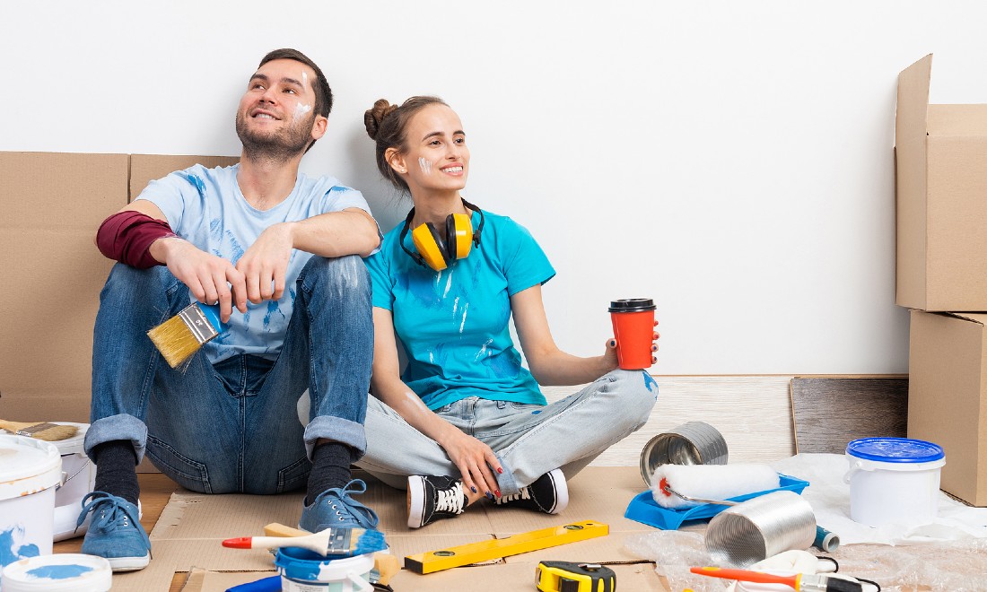 couple doing renovations sitting on floor happy