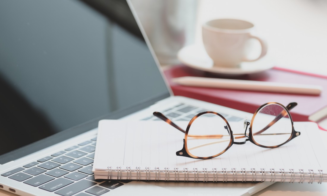 glasses on top of a notebook and laptop