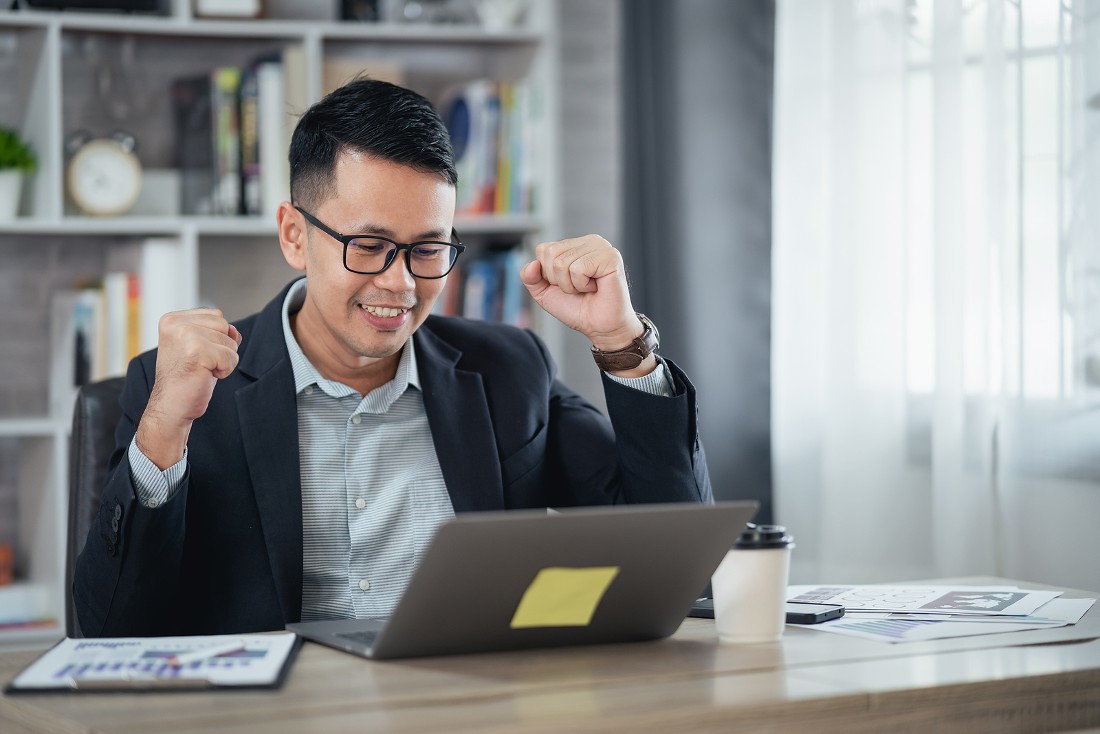 happy man with glasses looking at laptop