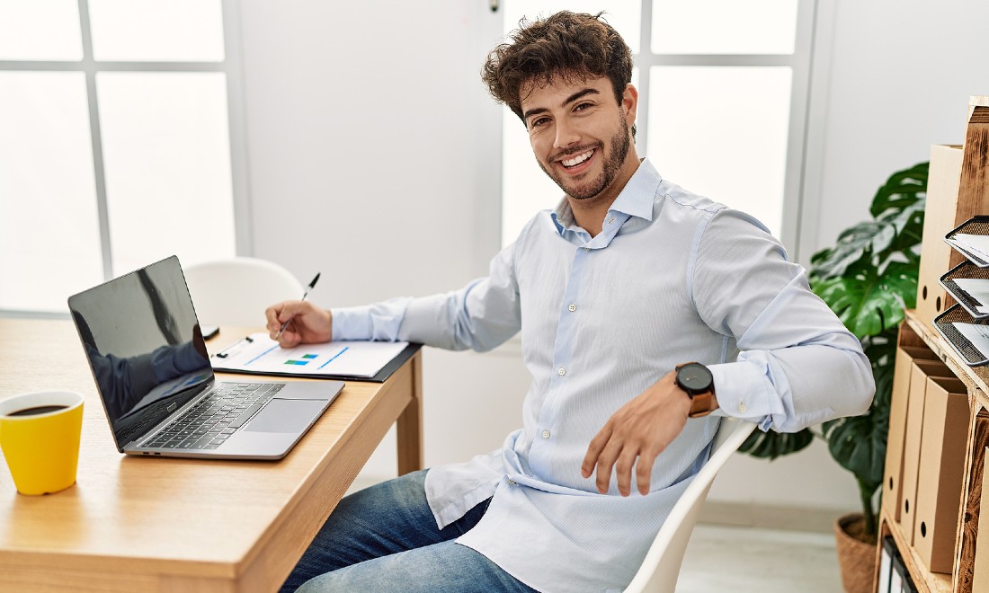 man behind laptop looking happy at camera