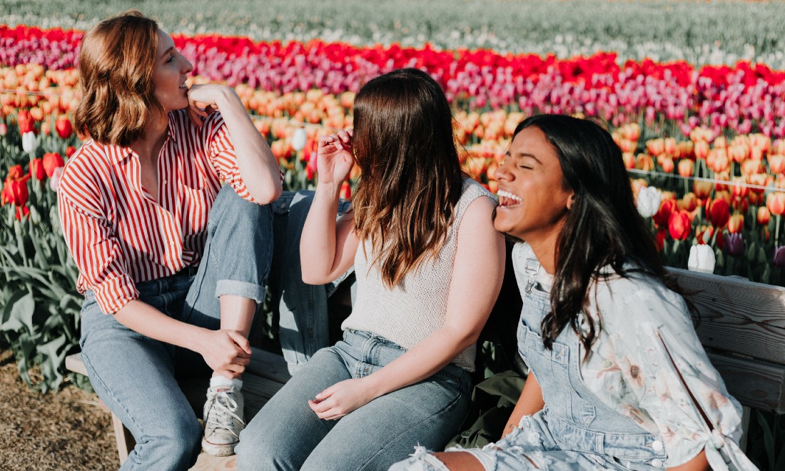 three women laughing on bench