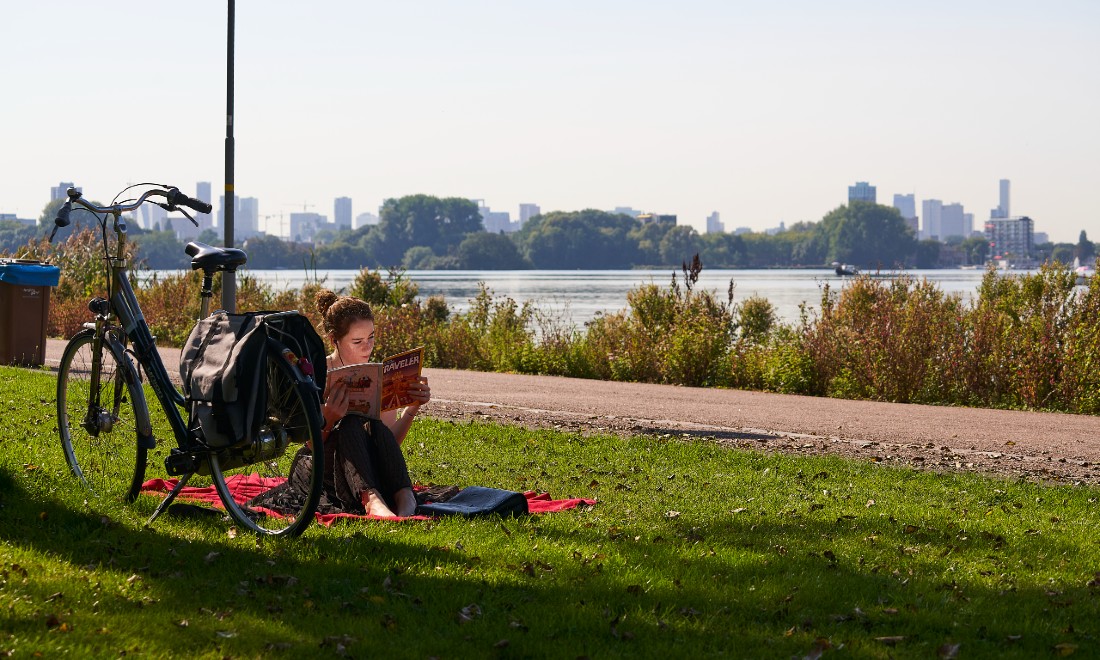 girl reading book on grass near bicycle