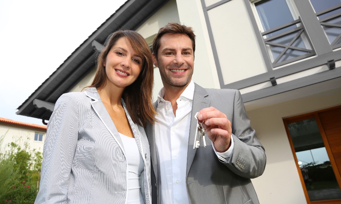 couple in front of house, holding up their new keys