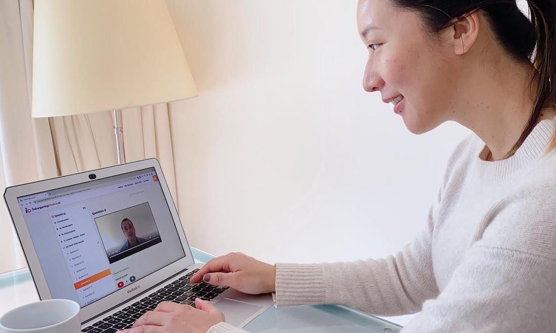 Woman studying for inburgering exam on laptop