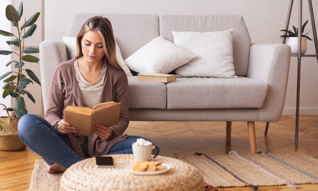 woman sitting in front of couch reading book