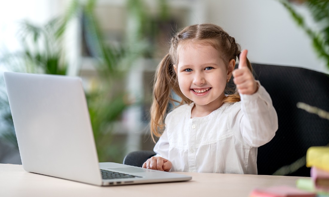 little girl behind laptop with thumbs up