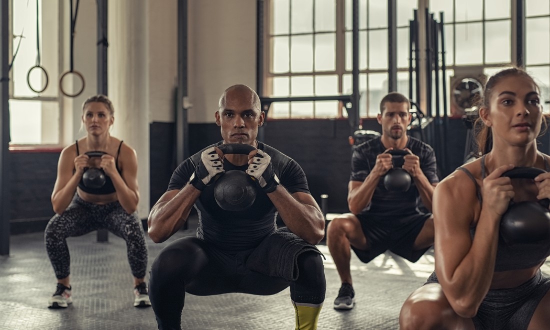 men and women in fitness centre with kettle bells