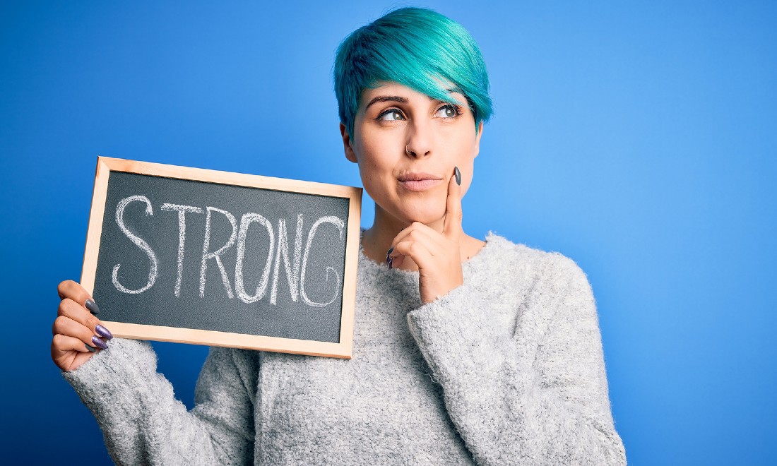 woman with blue hair holding up sign that says strong