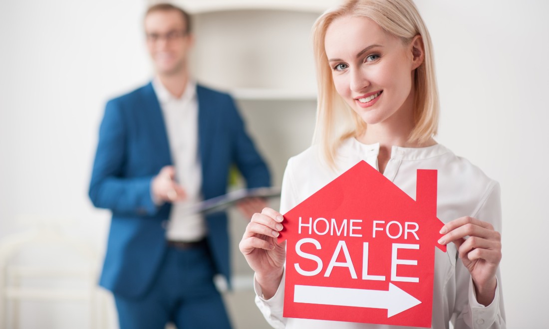 How to get the best offer when selling your property - woman holding for sale sign