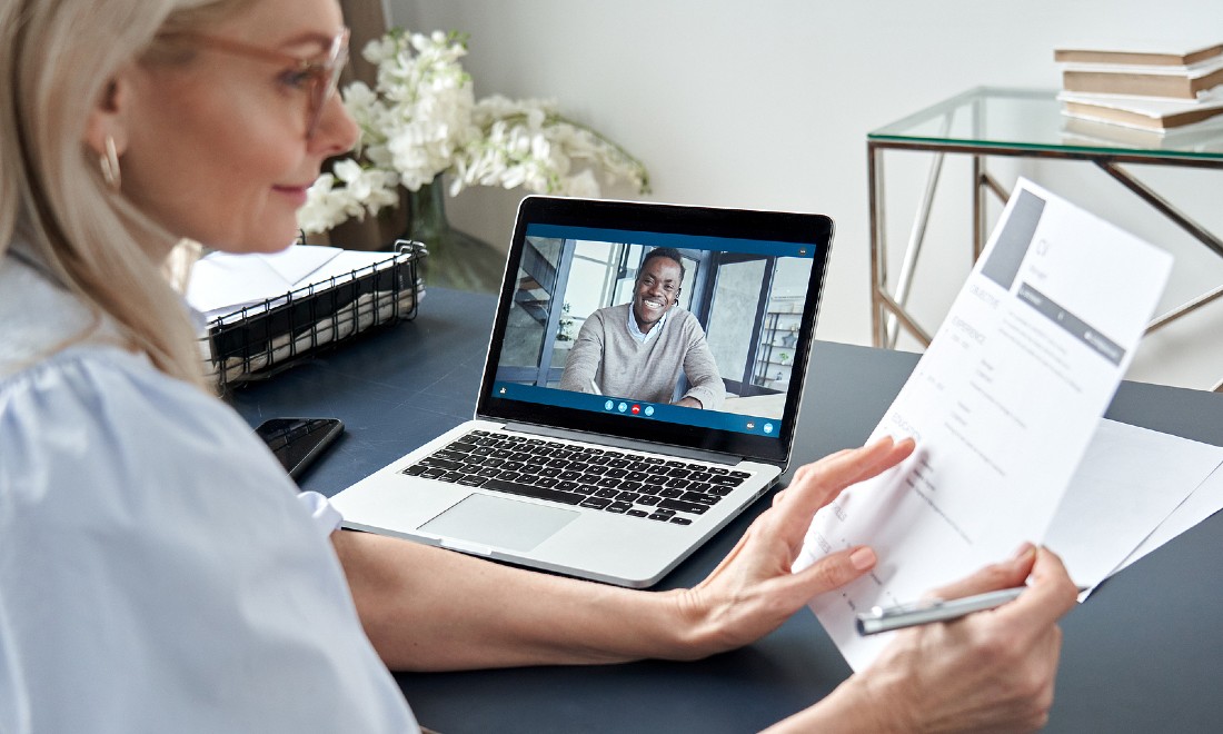 woman looking at CV while interviewing candidate online