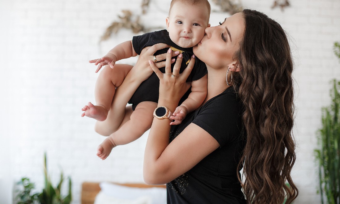 woman holding up baby who is smiling at camera