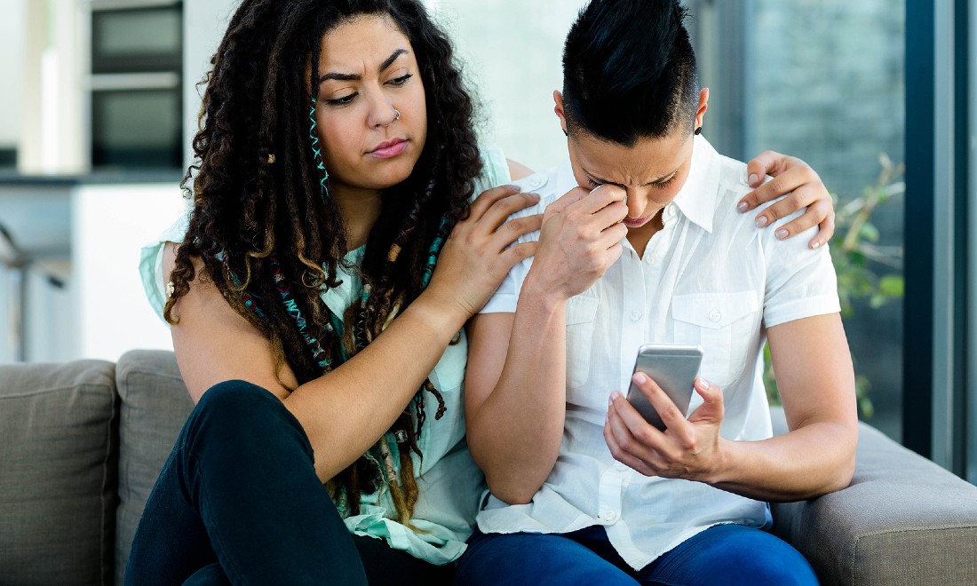 Couple on couch, one woman consoling other woman who is crying - How to help a partner with depression