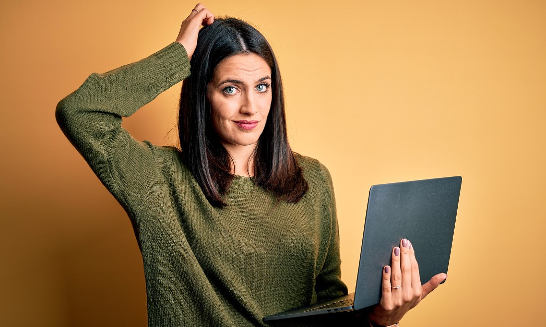 woman looking confused, holding laptop