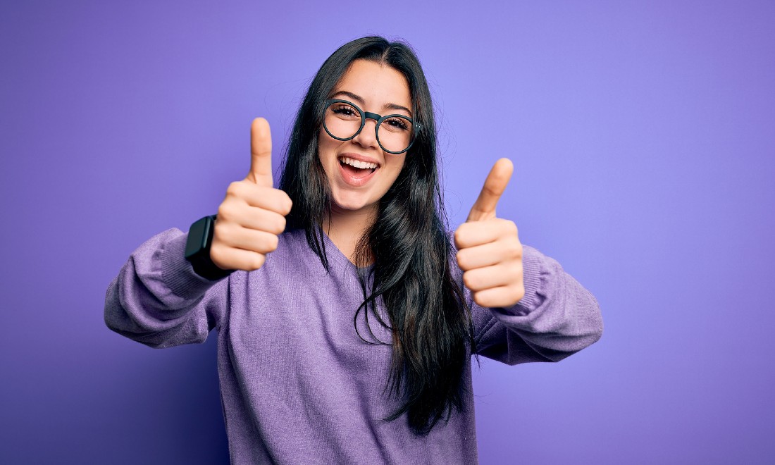 woman with two thumbs up purple background