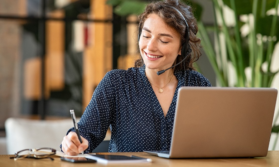 woman working on laptop with headphones in call centre