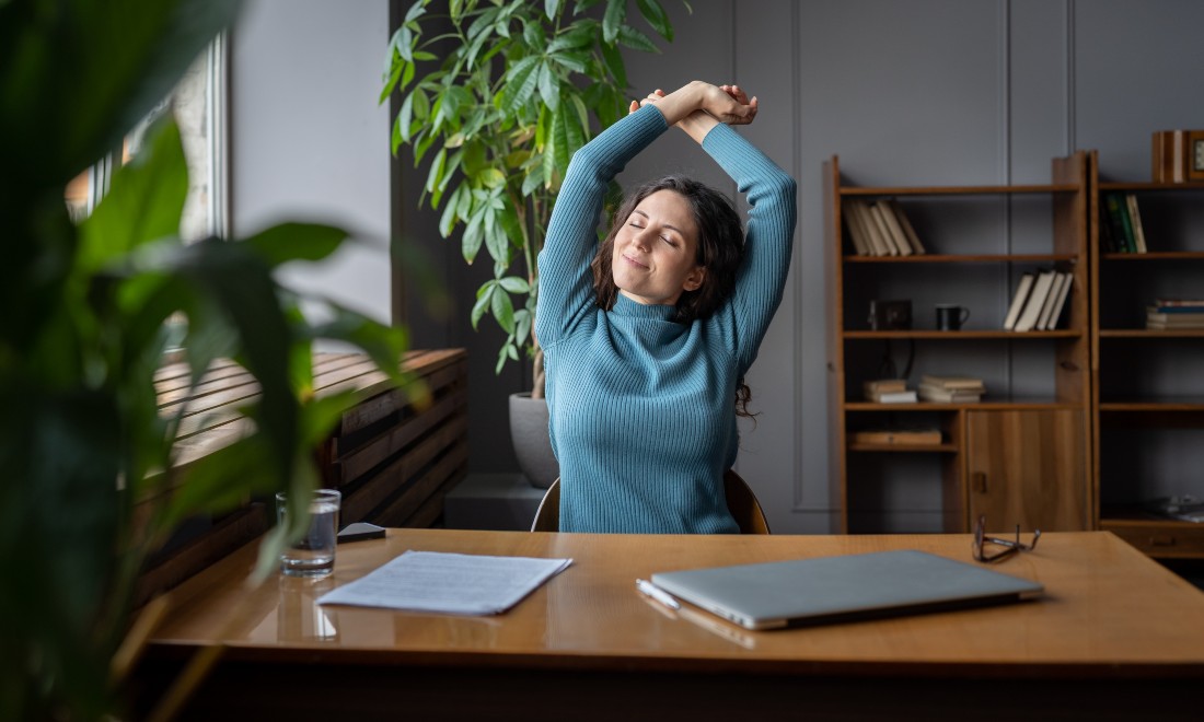 Woman sat at a desk, happy to be finished with work