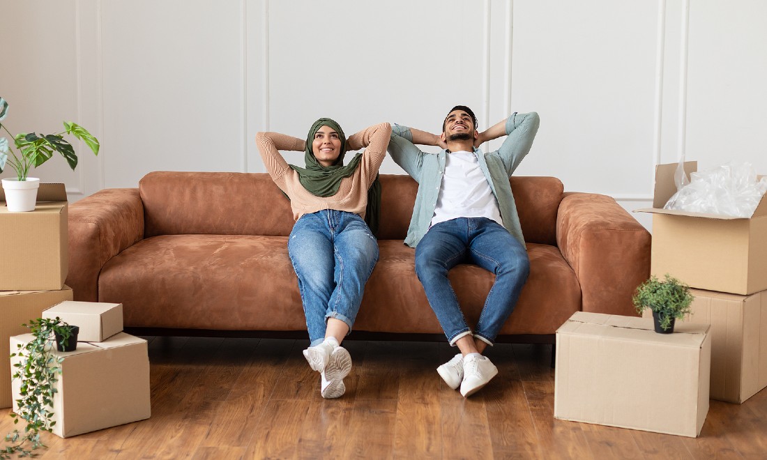 couple happy relaxed on couch, surrounded by moving boxes