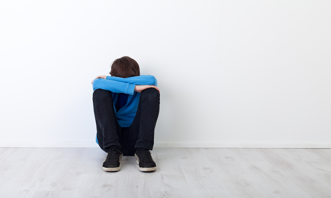 Teenager sitting head in arms