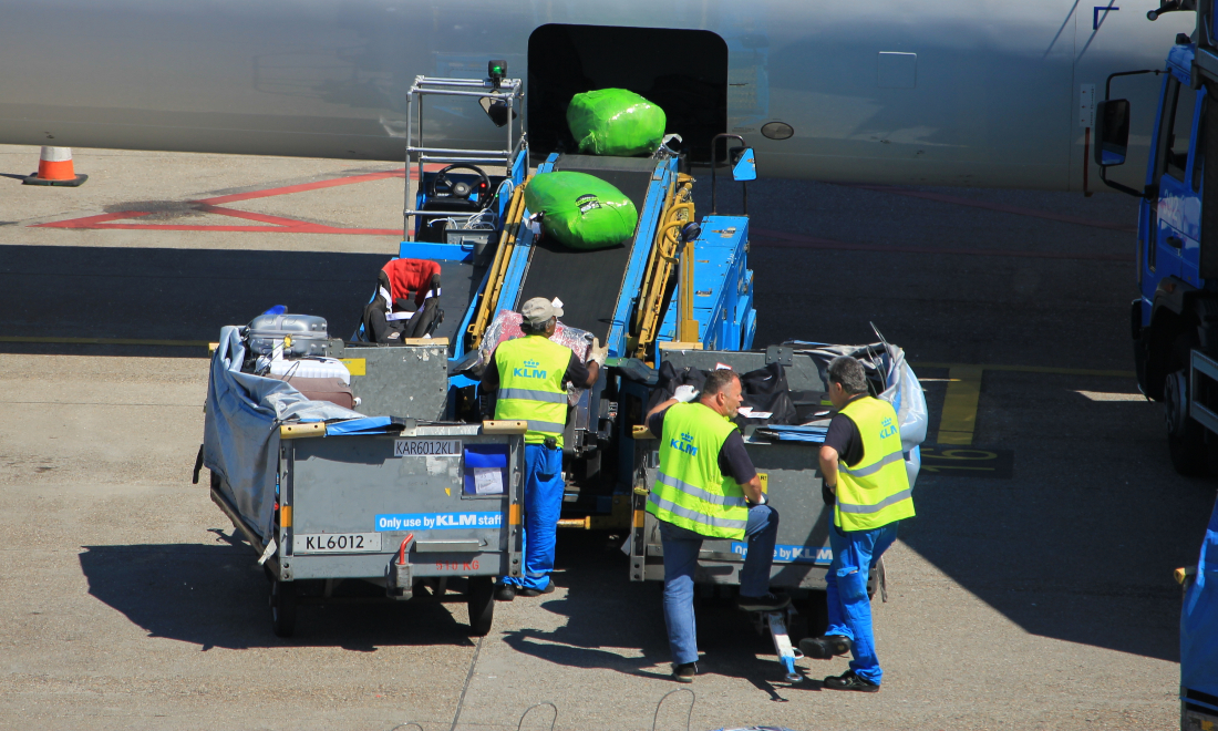 Baggage handlers loading luggage onto a KLM plane at Schiphol Airport