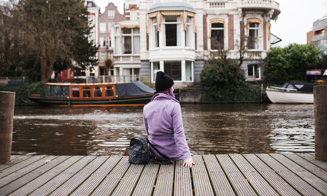 Girl sitting by canal in Amsterdam