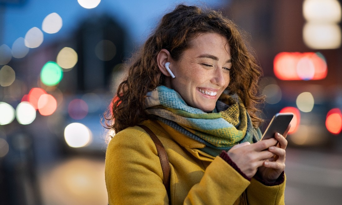 woman outside looking on smartphone, smiling