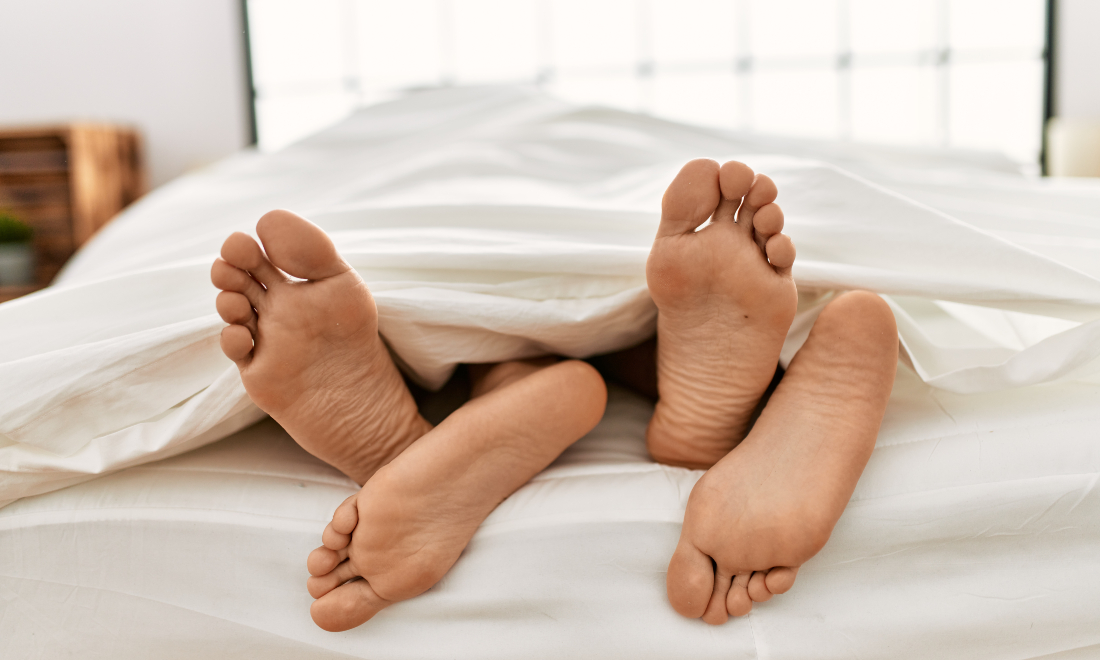 Feet of couple lying together in bed