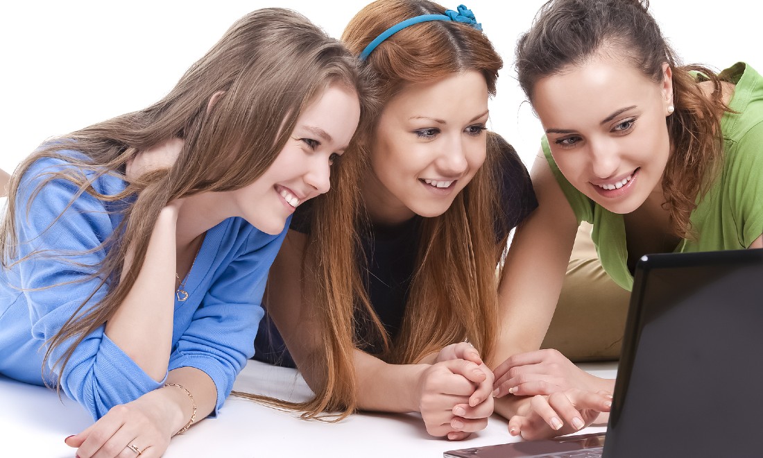 three young women using laptop