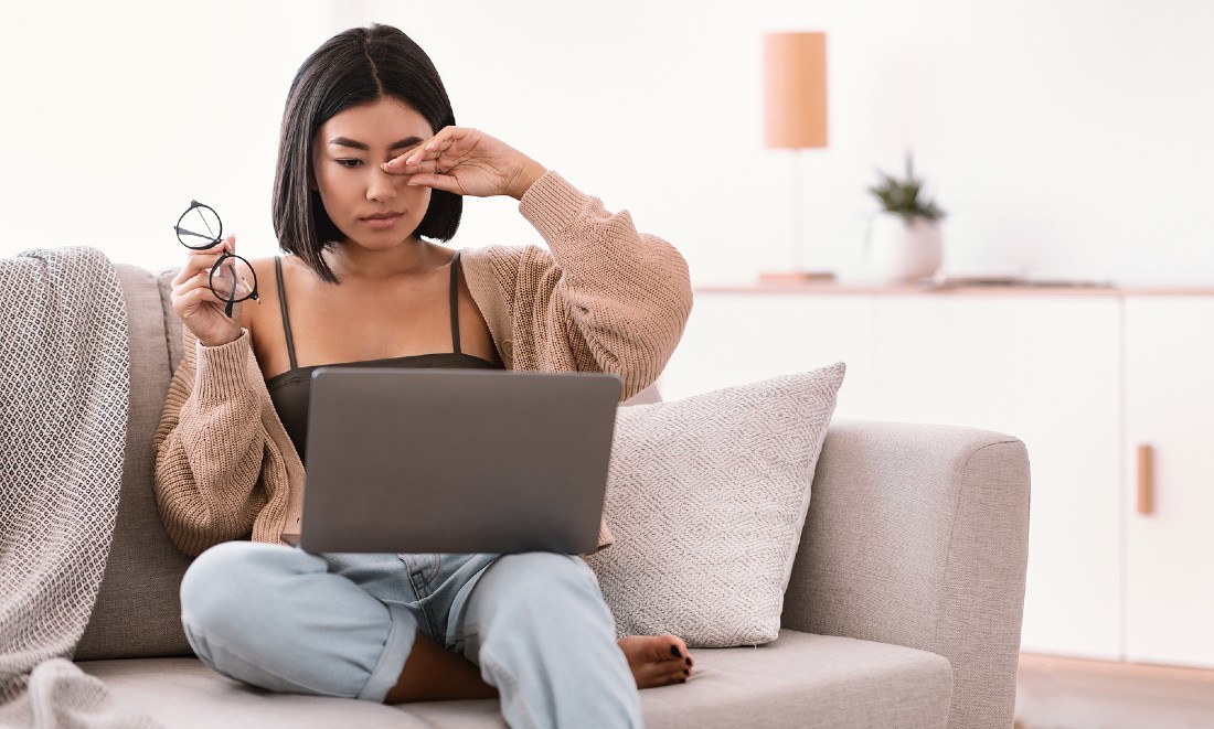 woman on couch in front of laptop tired