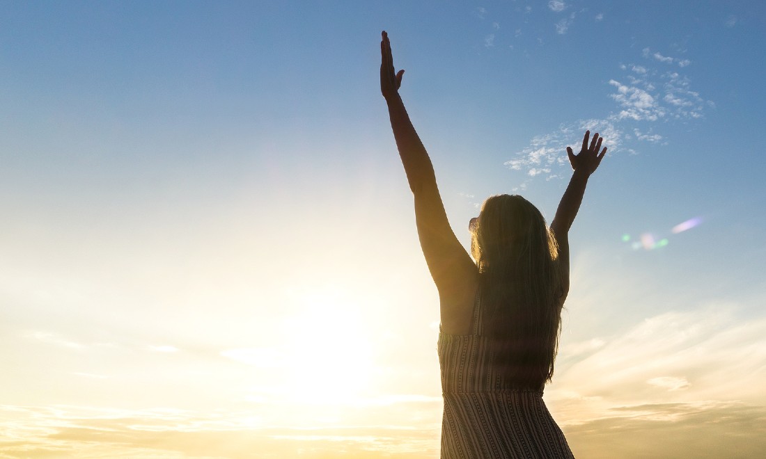 woman with hands up in air, sunset