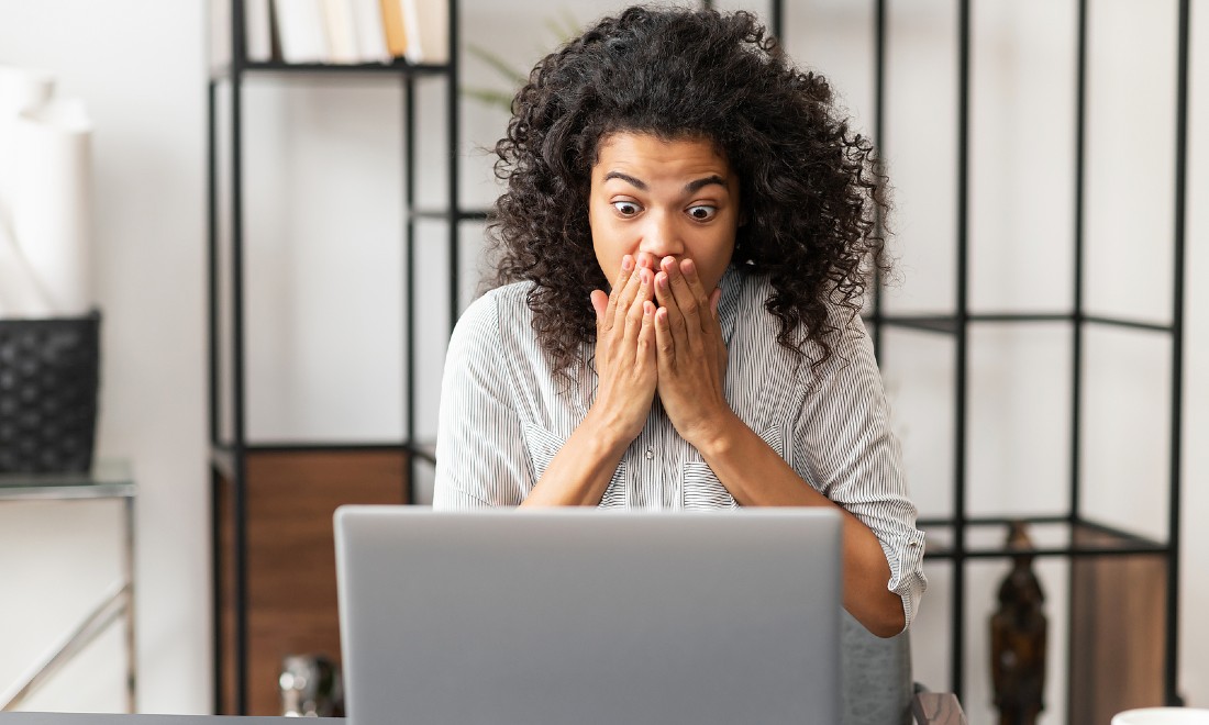 woman looking at laptop, shocked