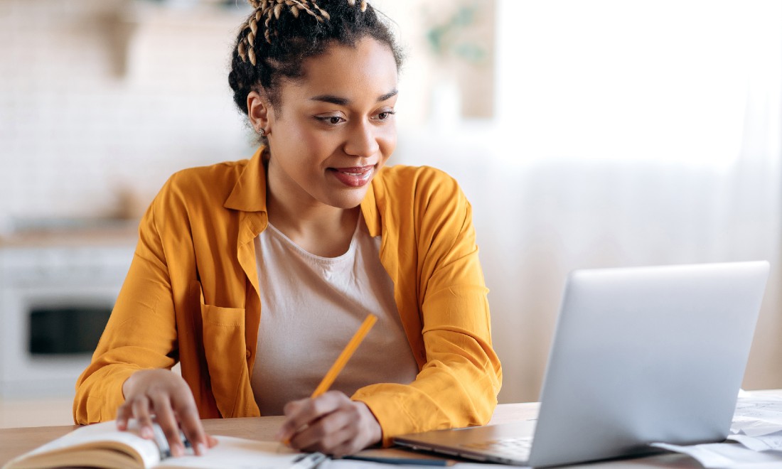 Young woman working from home, following online training course on her laptop