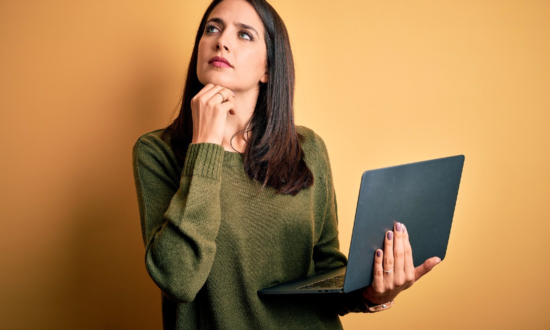 woman holding laptop, thinking, hand on chin