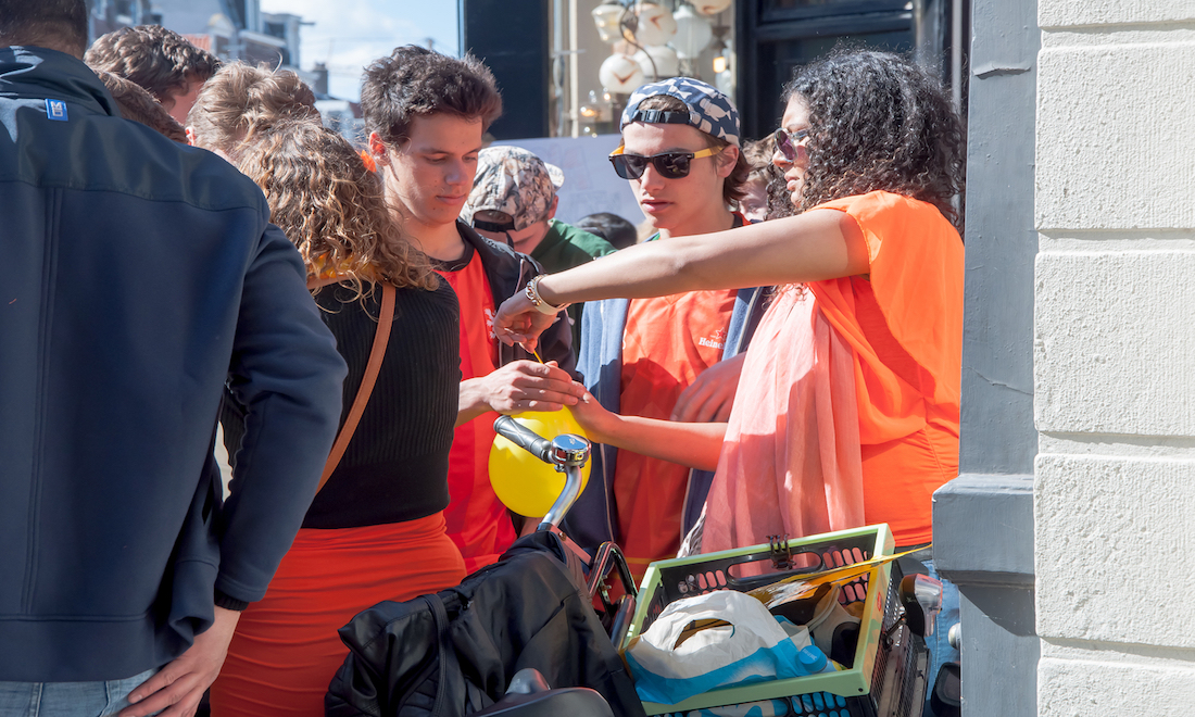 Woman selling laughing gas to two youths on Kings Day