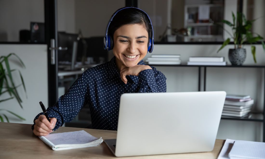 Woman studying behind laptop - Secrets to passing the Dutch speaking integration exam InburgeringOnline.nl