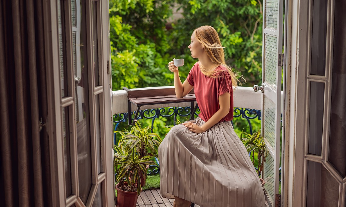 woman on balcony sipping tea